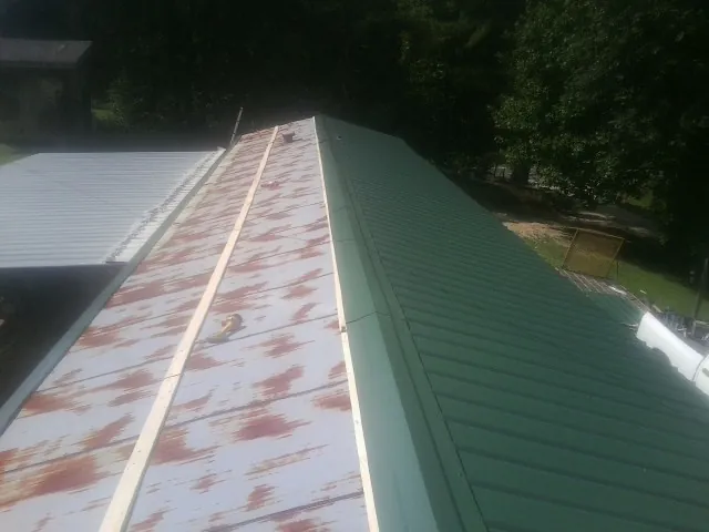 Old rusted panels beside newly installed green metal roofing — Wind Damage Roof Repair by Roofing Brothers in Trexlertown