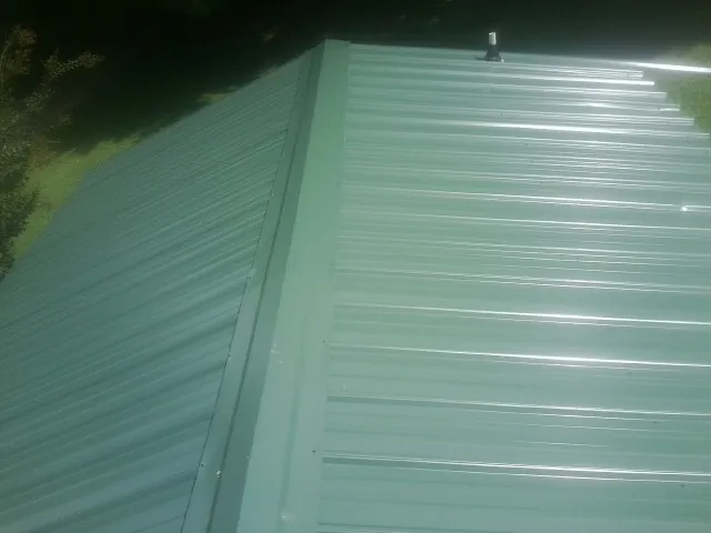 New green metal panels meeting at the ridge of a roof — Flat Roof Repair work by our crew in Trexlertown