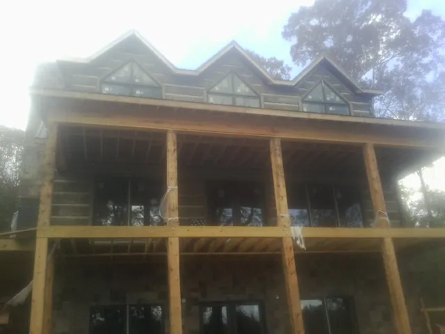 Dormers and porch framing on a large log home under construction — Roof Coating work by our crew in Trexlertown