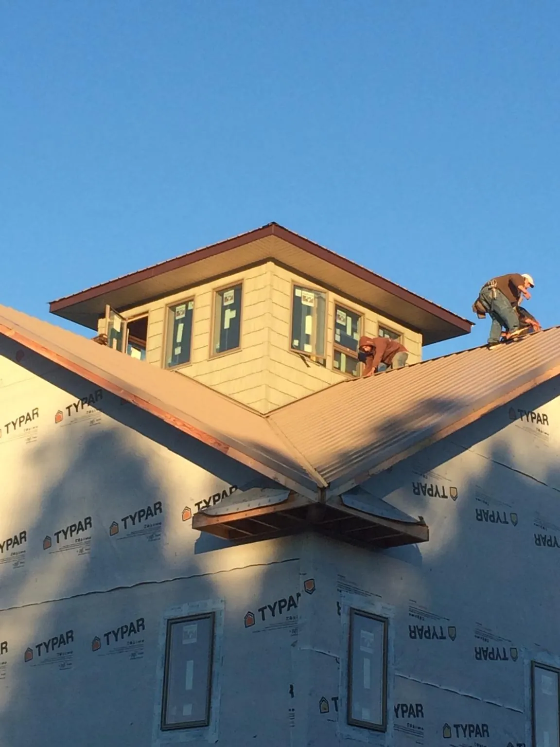 Roofers working around a rooftop cupola on a new metal roof at sunset — Roof Waterproofing in Trexlertown by Roofing Brothers